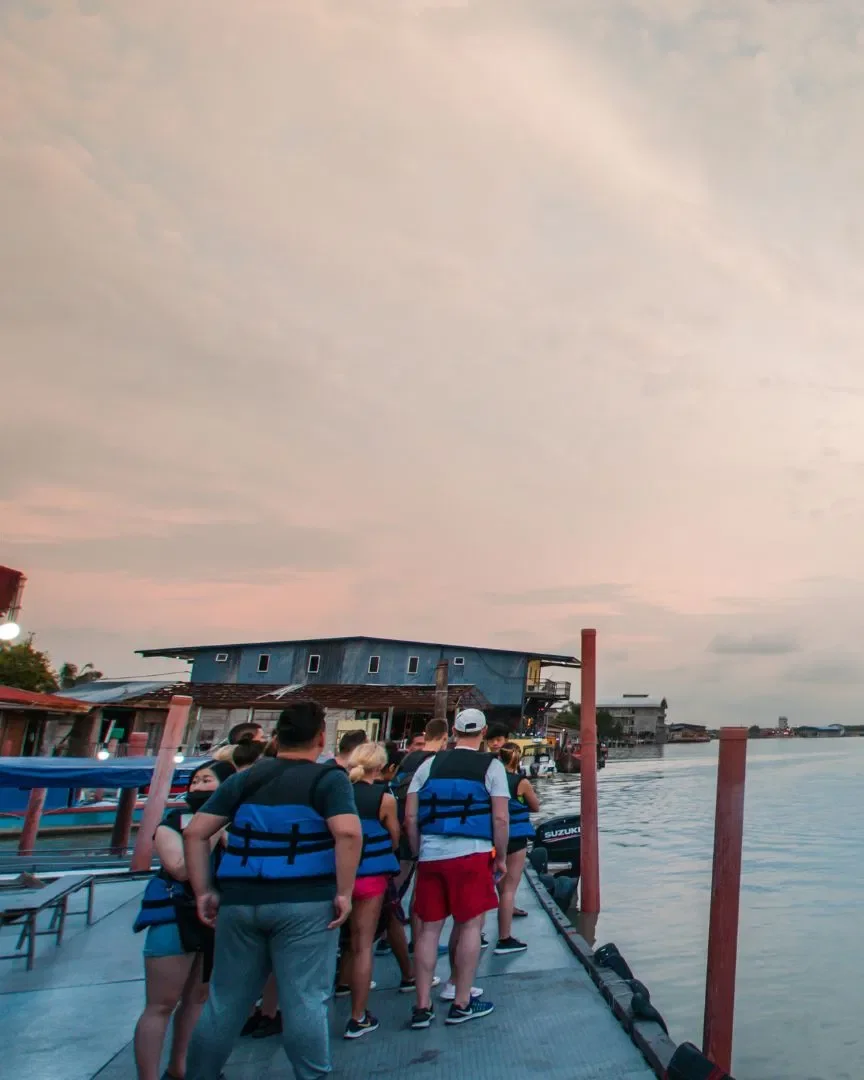 Guests in life jackets queuing on the jetty at Kuala Selangor at dusk